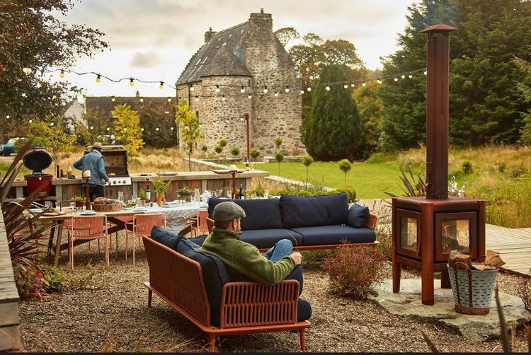 A large garden setting with garden furtniure, and a log burner