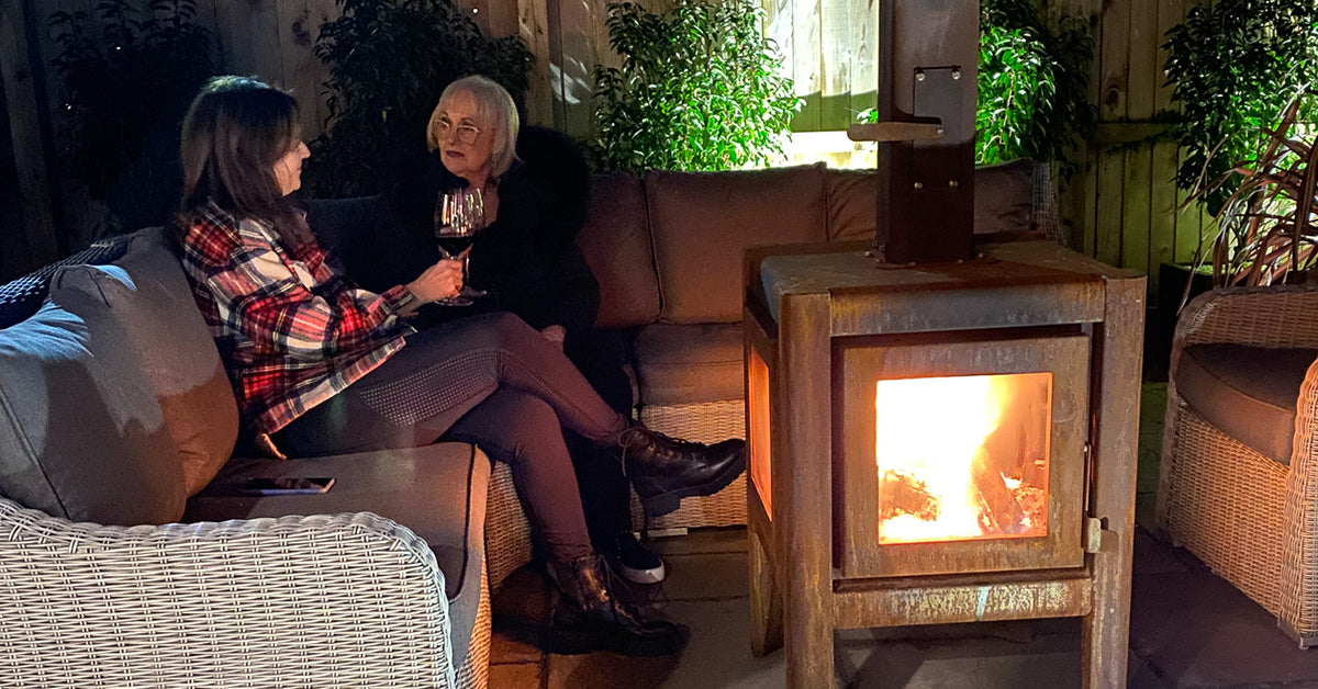 Two ladies enjoying a glass of wine next to an outdoor fireplace