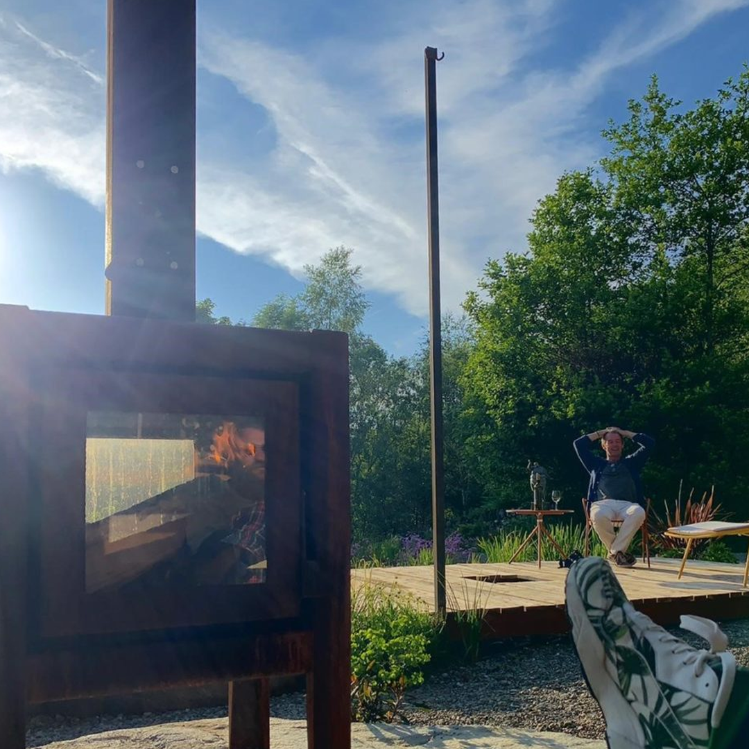 Two people outdoors next to the log burner