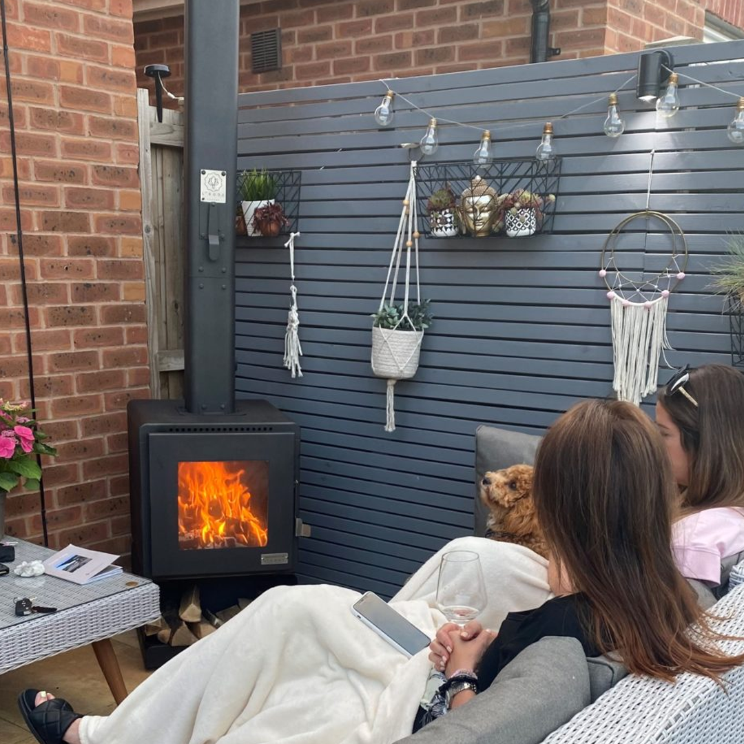 L'Bode Urban Black Edition Wood Burner in outdoor setting with two ladies